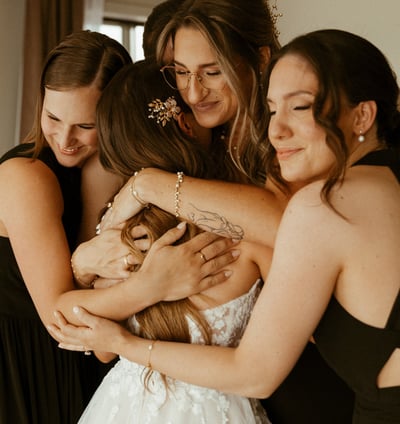 Four emotional bridesmaids embracing the bride.