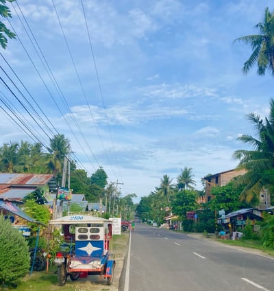Siquijor road with accommodations and a tricycle on the road side