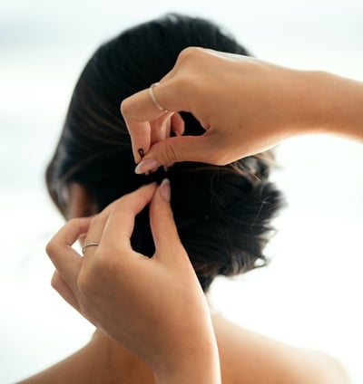 Hairstylist adding a bobby pin to the bride's hair.