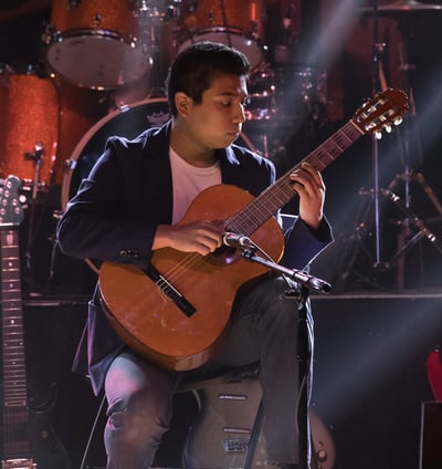 Gurnee Guitar Academy Guitar Lessons a man playing classical guitar in a concert