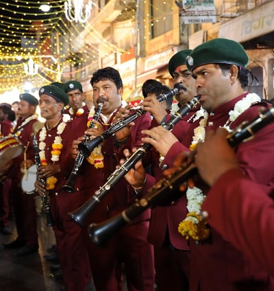 Crew members of the Manohar Brass Band playing clarinet, shehnai, and thap dhol instruments during a traditional performance.