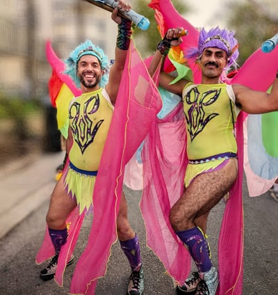two men in colorful costumes are dancing in the street