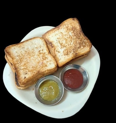 alt="Toasted Veg Sandwich served with spicy green chutney and sweet red sauce on a white plate"