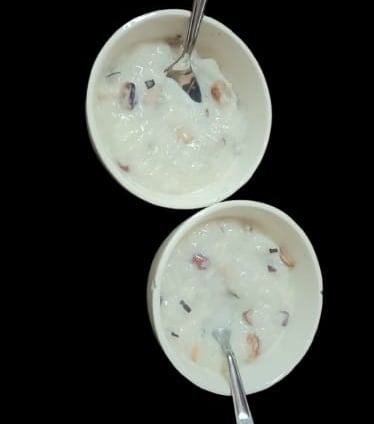 alt="Traditional Kheer served in a bowl with a spoon, containing rice, almonds, raisins, and saffron