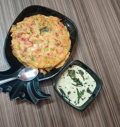 alt="Crispy and fluffy Uttapam served with coconut sauce on a wooden table"