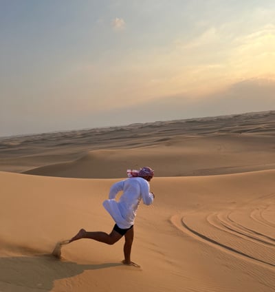 a man in a white shirt is running through the desert