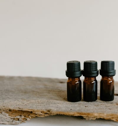 three bottles of essential oils on a wooden surface