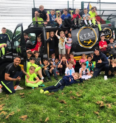 a big group of children by the NEAT fun bus