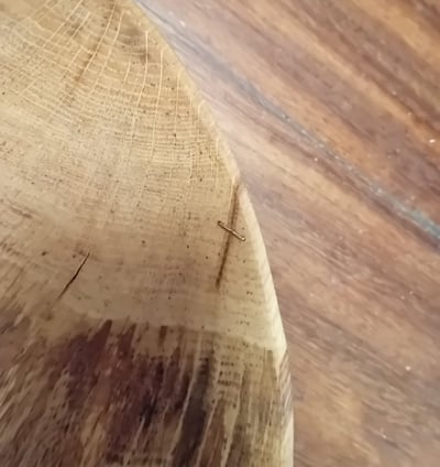 close-up of the edge of a bowl with a copper wire threading together 2 sides of a small crack