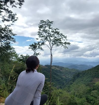 a woman sitting on a rock with a view of the mountains