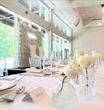 White rose flower wall with matching white roses in vases with tableware
