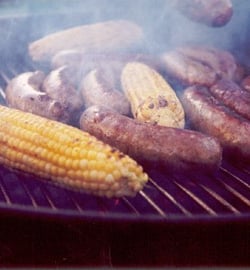 bratwurst on a grill with corn on the cob