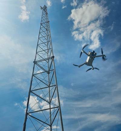 Drone voert visuele inspectie uit bij hoge zendmast onder een heldere hemel