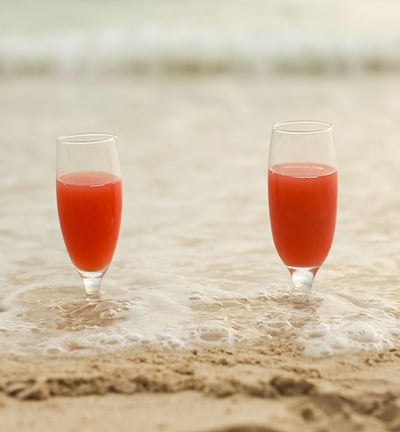 two cocktails buried in the sand on the beach