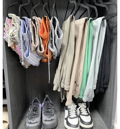 Colorful shorts and pants neatly hung above sneakers in a modern organized closet.