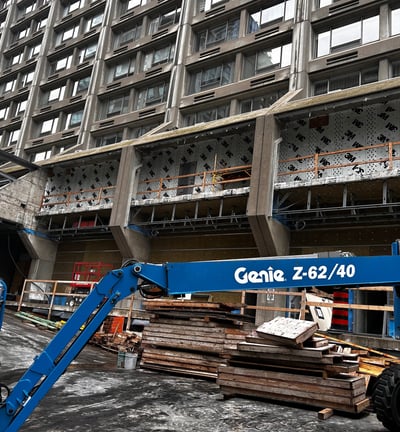 a crane lifts a load of wood to a building