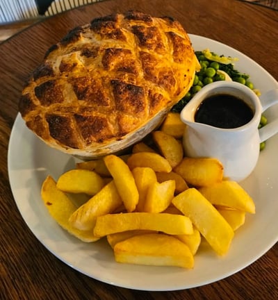 a pie with a mug of gravy and some chips