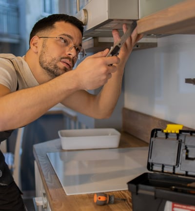 a handyman in overalls is installing a cabinet