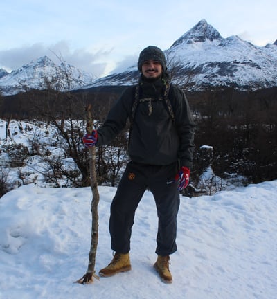 a man standing in the snow with a stick in his hand