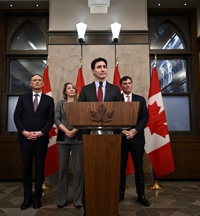 a man in a suit and tie standing at a podium with two other people