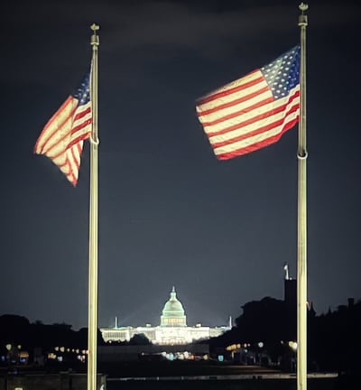 two flags are flying in the sky over Capitol Hill in Washington DC