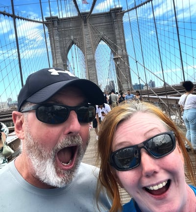 Two people looking happy on Brooklyn Bridge