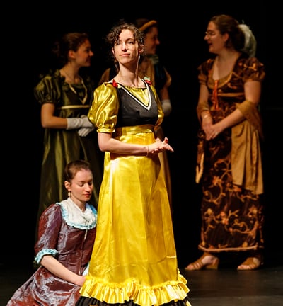Aude Fy, en costume d'époque jaune dans une pièce de théâtre, interprétant une cantatrice