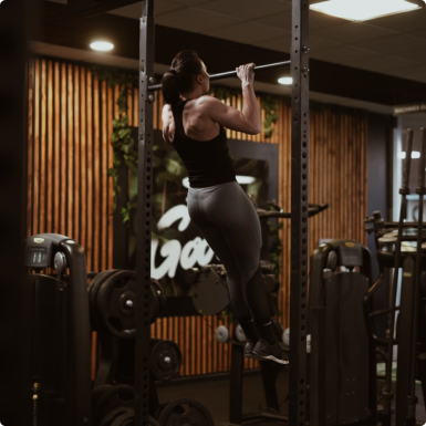 a woman doing a pull up barbell in a gym