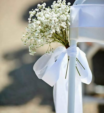 Silla para boda decorada con un liston blanco y flores