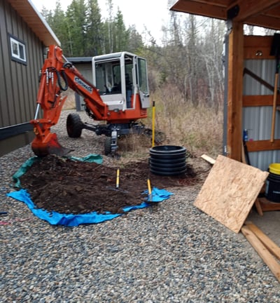 Compact spider excavator installing a test pit in confined area