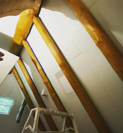 drywall ceiling install with exposed log beams