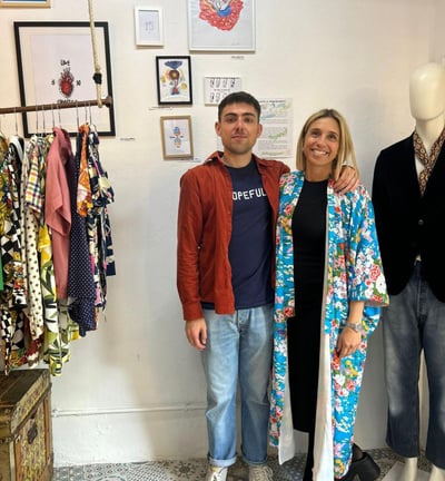 a man and woman standing in front of a display of clothing