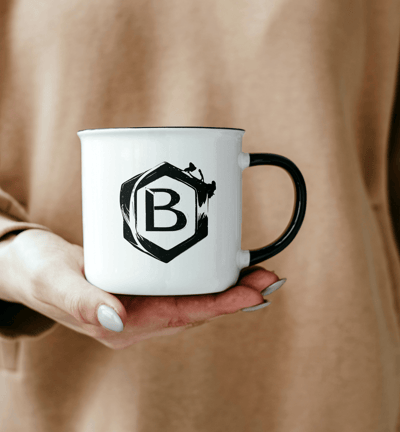 a person holding a mug with a black and white logo