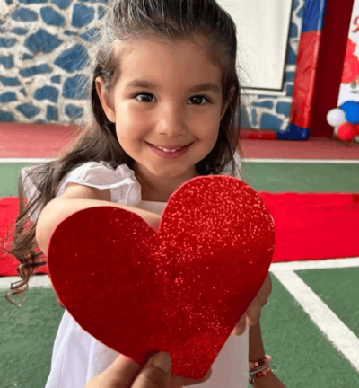 Uma aluna da educação infantil do centro educacional florescer segurando um coração de EVA