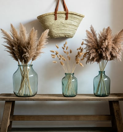 three vases with dried grass in them