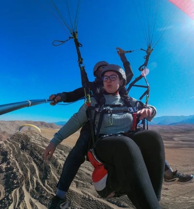 A young woman flying in a paraglider, enjoying the experience.