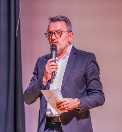 Un animateur de conférence avec un micro et des fiches dans les mains qui parle