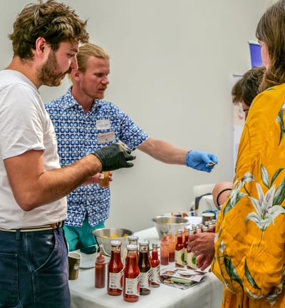 Groupe de personnes autour d'un stand qui dégustent des sauces pimentées