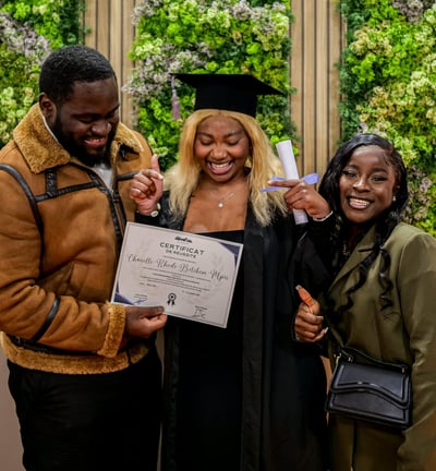 Une étudiante qui pose avec sa famille et son diplôme dans les mains