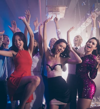 Excited group dancing and posing in a downtown Vegas nightclub with vibrant lights and party energy.