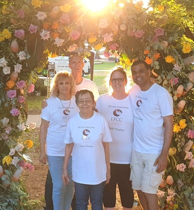 a group of people standing in front of a flower arch