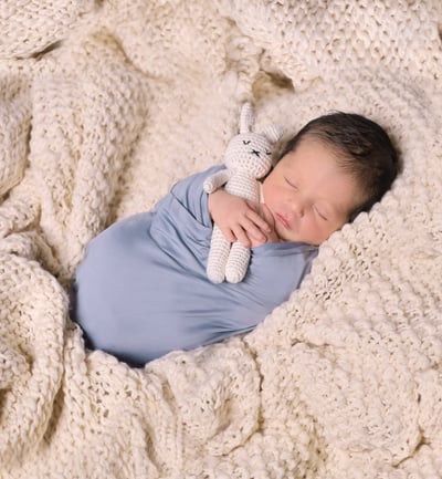 a baby boy is sleeping in a blanket