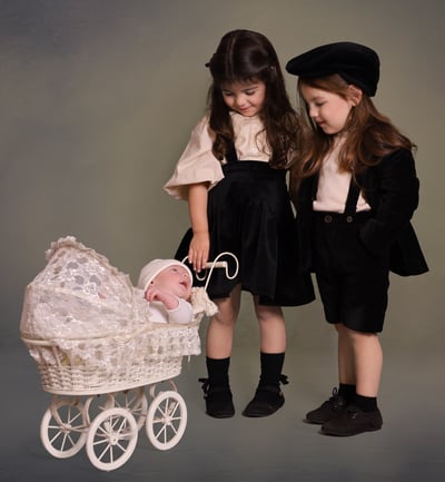 two kids in black dresses and hats are standing next to each other looking at baby