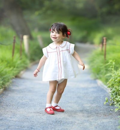 a little girl walking down a path with a red shoe