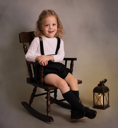 a little boy sitting in a rocking chair