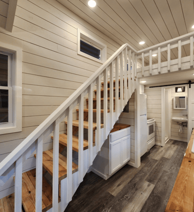 Wooden stairs and loft inside bright tiny home on wheels