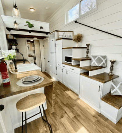 Cozy kitchen and stairs inside modern tiny home on wheels