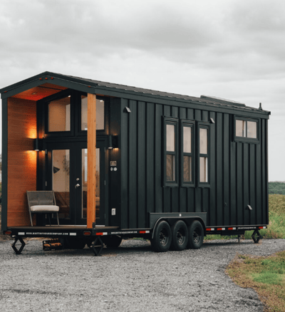 Sleek black modern tiny home on wheels with porch seating