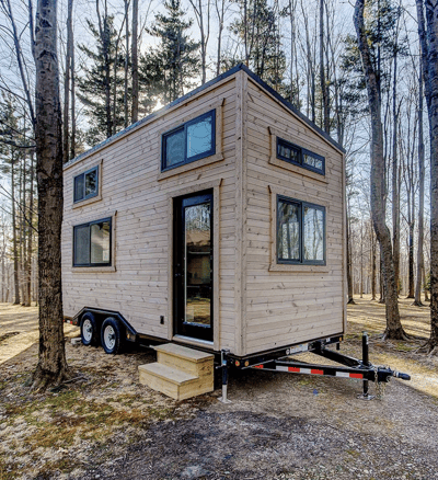 Compact wooden tiny home on wheels parked in the forest