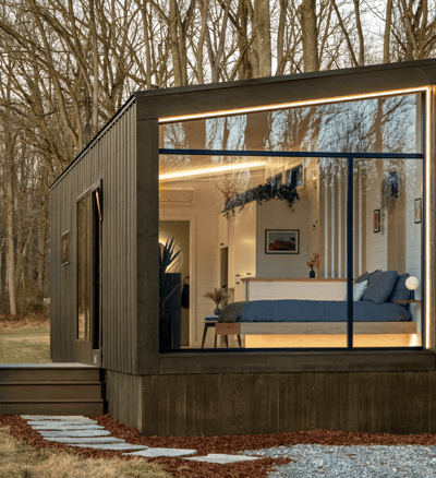 Modern tiny home on wheels with large glass windows in nature